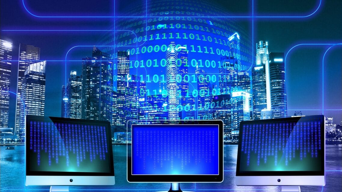 Kolme tietokoneruutua ja digitalisaatioon liittyviä koodeja symboloivia numerosarjoja sinisellä taustalla.